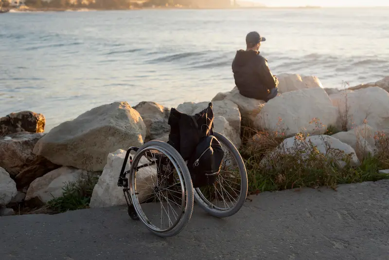 Photo d'un homme près de son fauteuil roulant qui regarde la mer