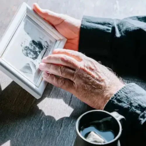 Photo d'un vieil homme qui regarde un portrait de femme